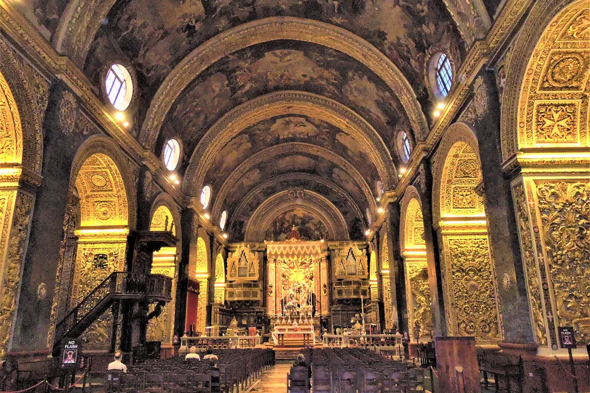 La navata della Concattedrale di San Giovanni verso l'altare, con una volta a botte dipinta sopra e pareti ricoperte di intagli dorati