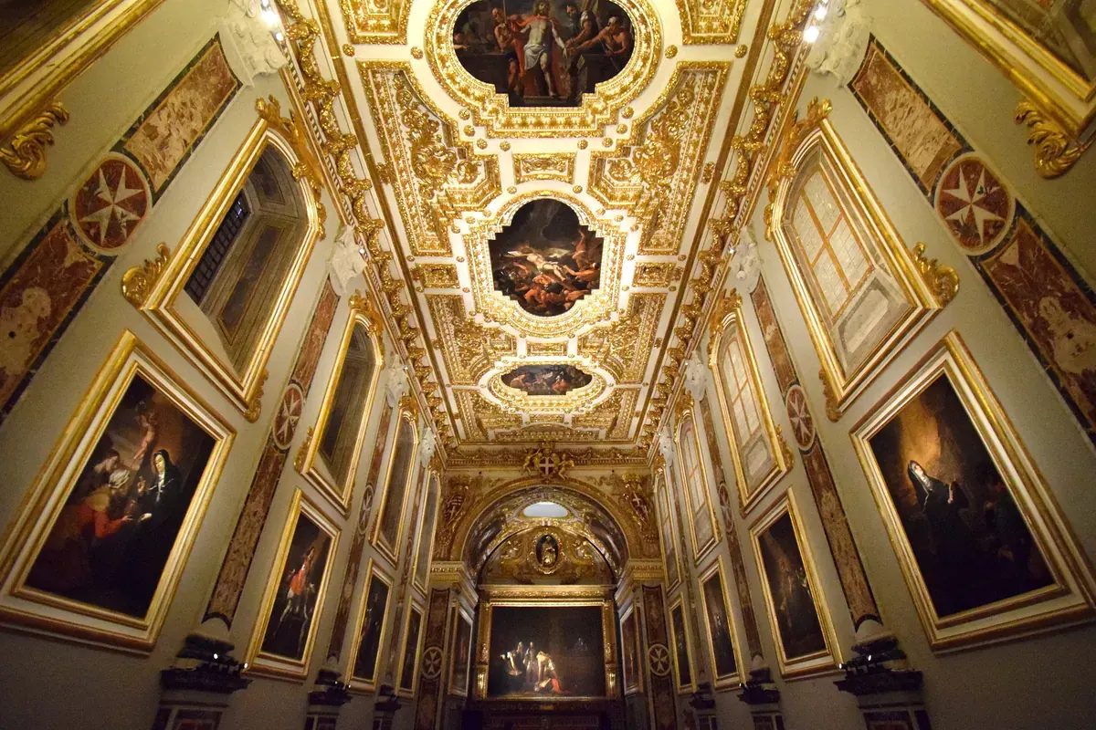 L'Oratorio della Concattedrale di San Giovanni, una stretta sala dorata adorna di grandi dipinti, con la Decollazione di San Giovanni Battista del Caravaggio in fondo