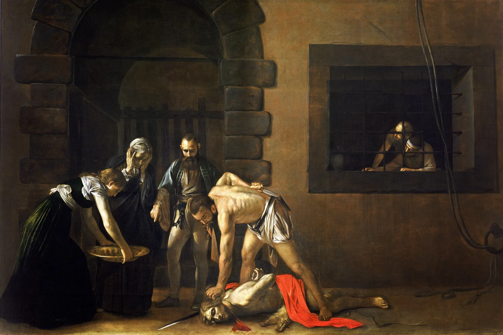 La Decollazione di San Giovanni Battista del Caravaggio: un carnefice chino sul santo caduto in un cupo cortile di prigione, con una donna che regge un vassoio d'oro e due prigionieri a una finestra inferriata